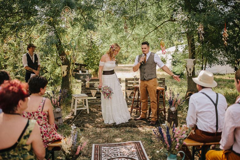 Outdoor wedding celebration in a wooded setting with vintage-style decorations.