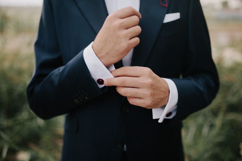 Close-up of hands adjusting formal suit cuff links and sleeve.