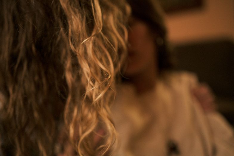 Close up of curly blonde hair with soft focus background in warm lighting.