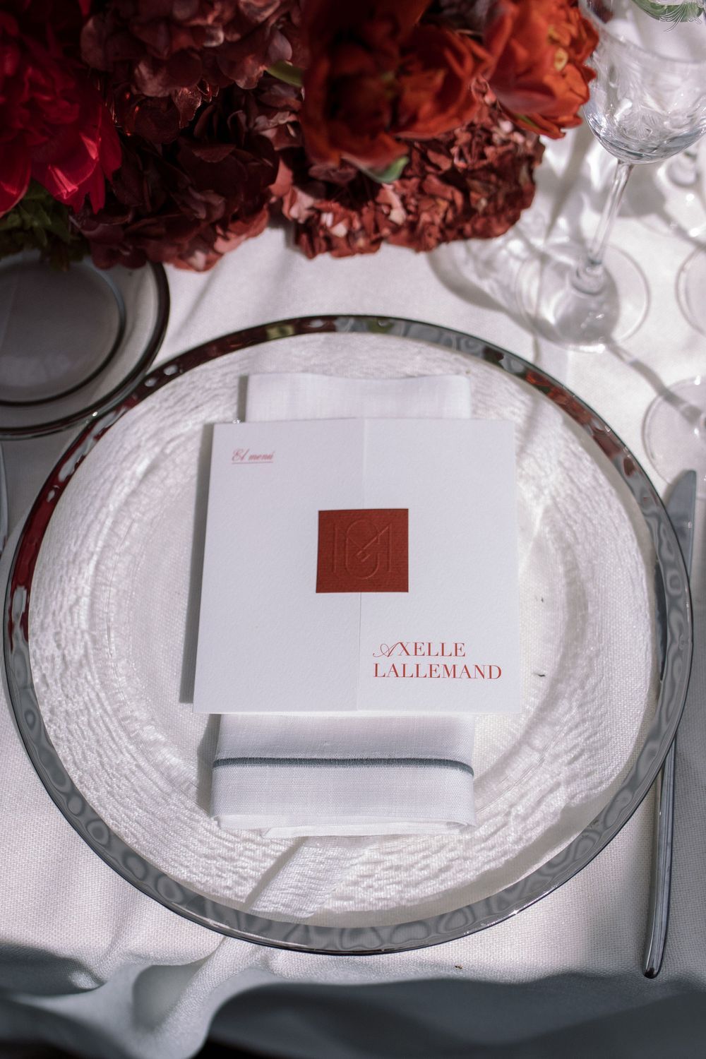 An elegant place setting with white plate and menu card decorated with a red wax seal.