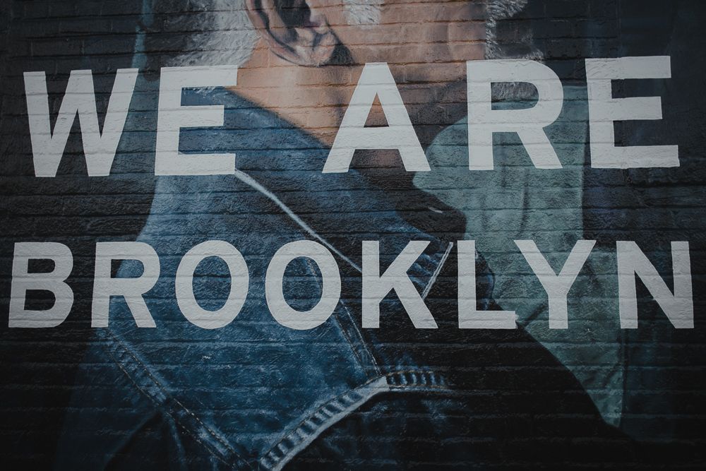 Street art mural reading 'WE ARE BROOKLYN' painted on urban wall.