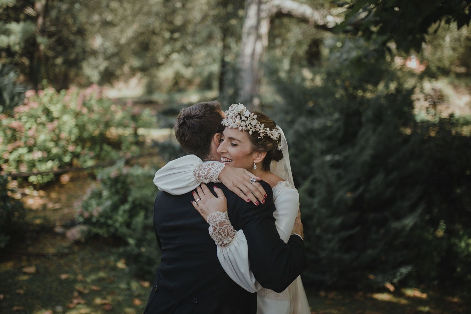 Intimate embrace between newlyweds in garden setting with autumn foliage.