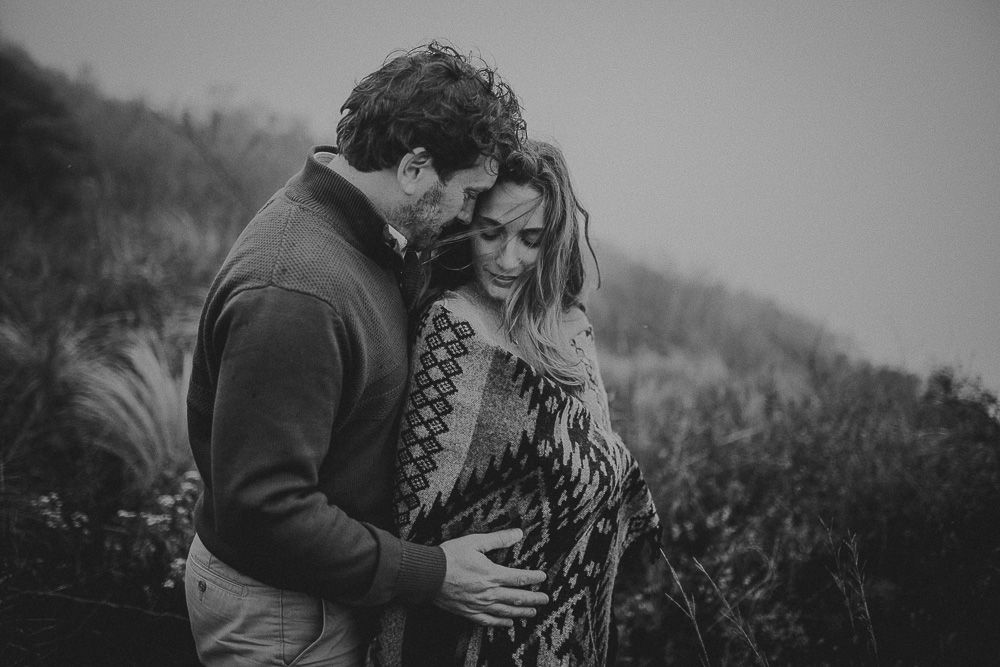 A romantic black and white moment shared between a couple embracing outdoors on a misty day.