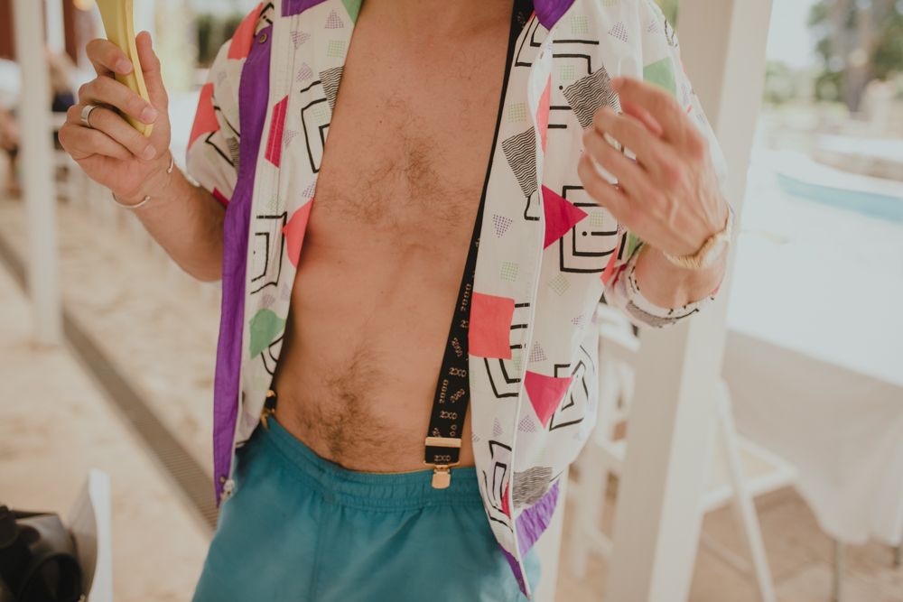 Person wearing geometric print shirt and turquoise shorts at pool party.