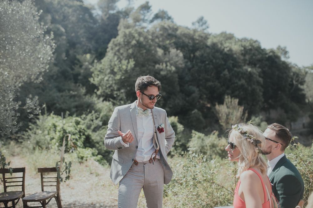 Outdoor wedding scene with guests gathered in a sunny garden setting.