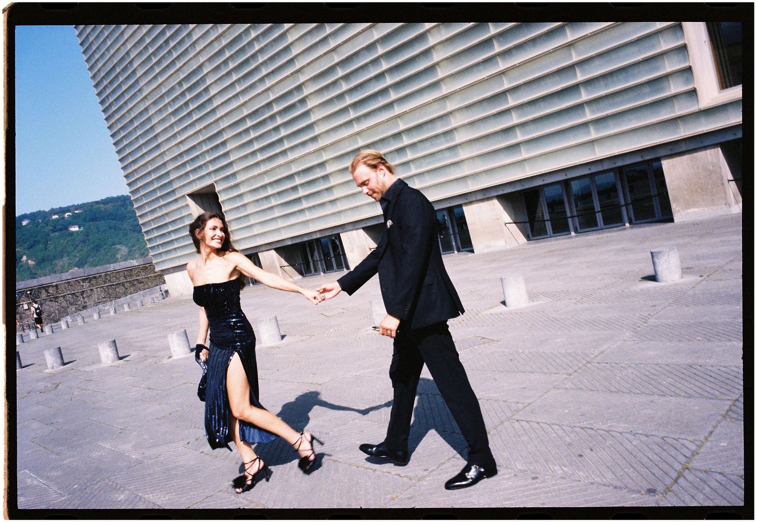 A sequence of dance moves showing two people performing elegant steps on a paved outdoor area near a modern building.