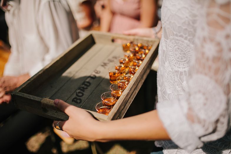 A wooden box filled with golden rings displayed on lace fabric.