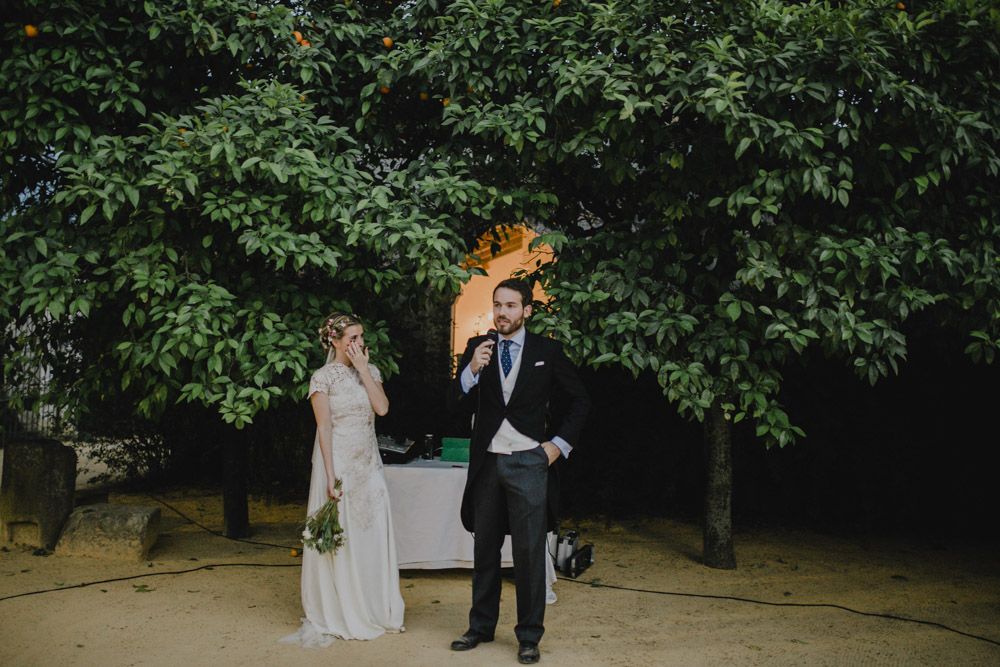 A romantic wedding couple illuminated by sparklers at night in a garden setting.
