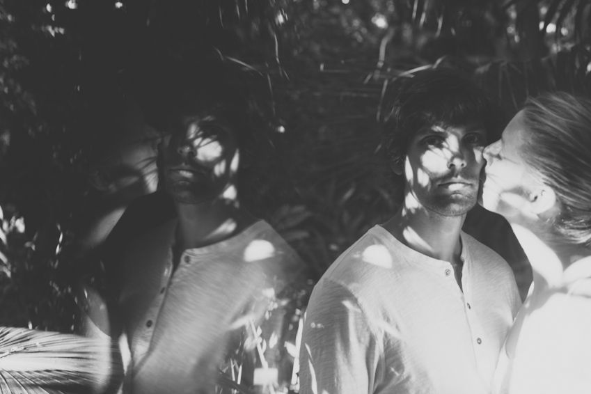 A dreamy black and white photo of a couple in dappled sunlight.