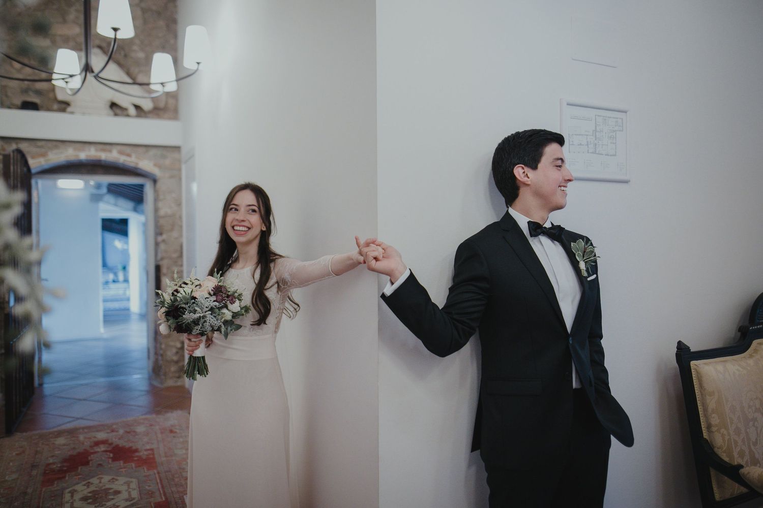A joyful couple poses on their wedding day with the bride holding a bouquet and groom in black tuxedo.