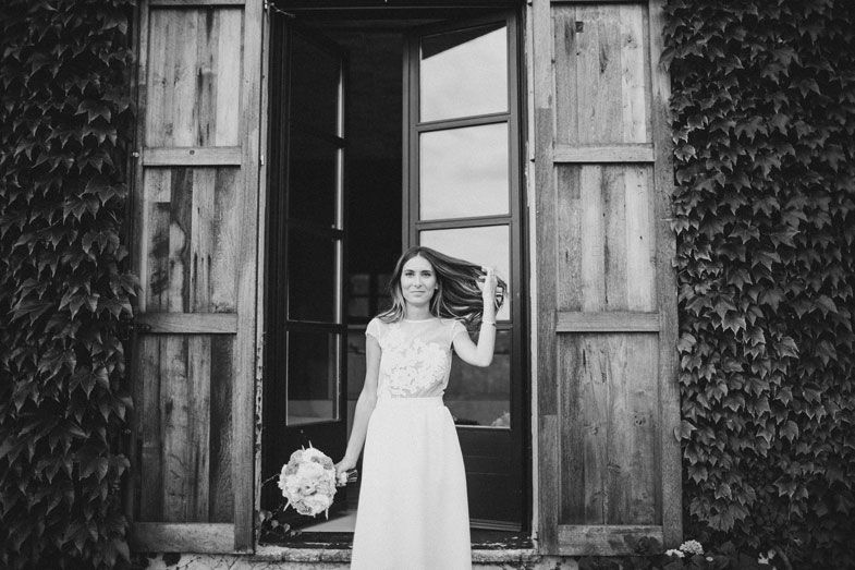 Black and white photo of a bridal figure standing in a rustic doorway framed by ivy.