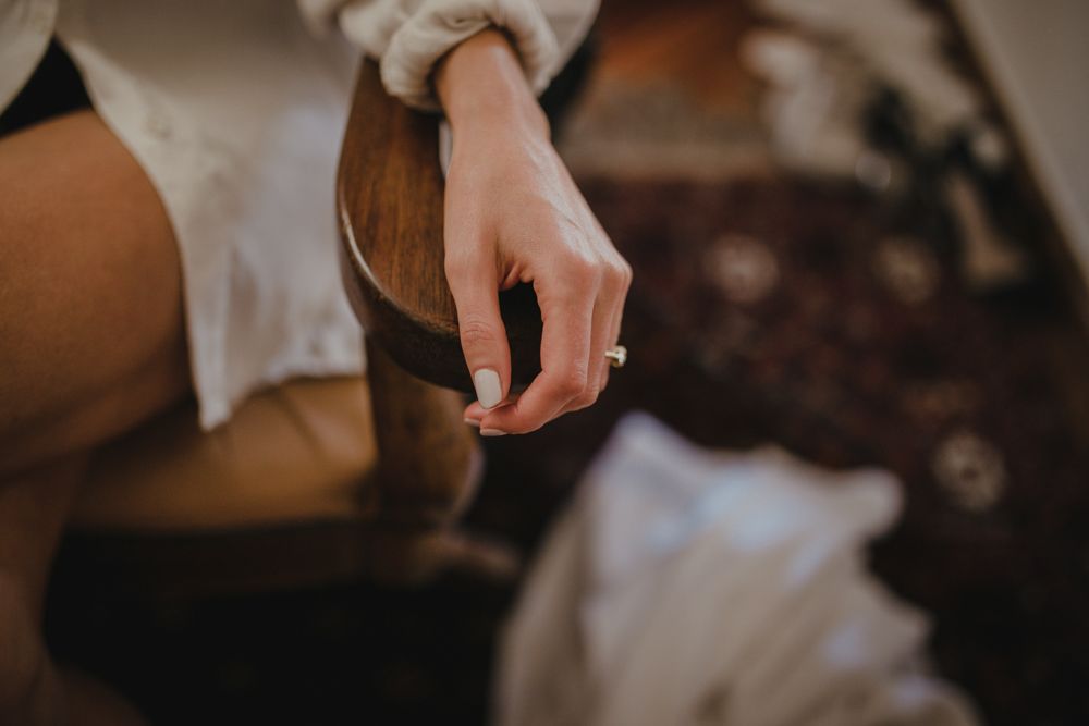 A close-up shot of a hand near a wooden surface in moody lighting.
