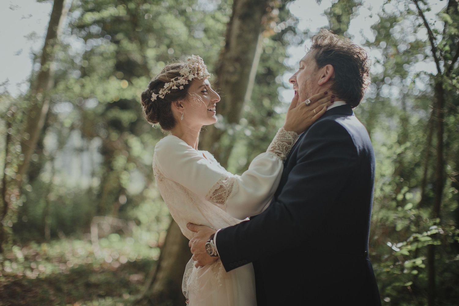A romantic moment between newlyweds in a forest setting with soft natural lighting.