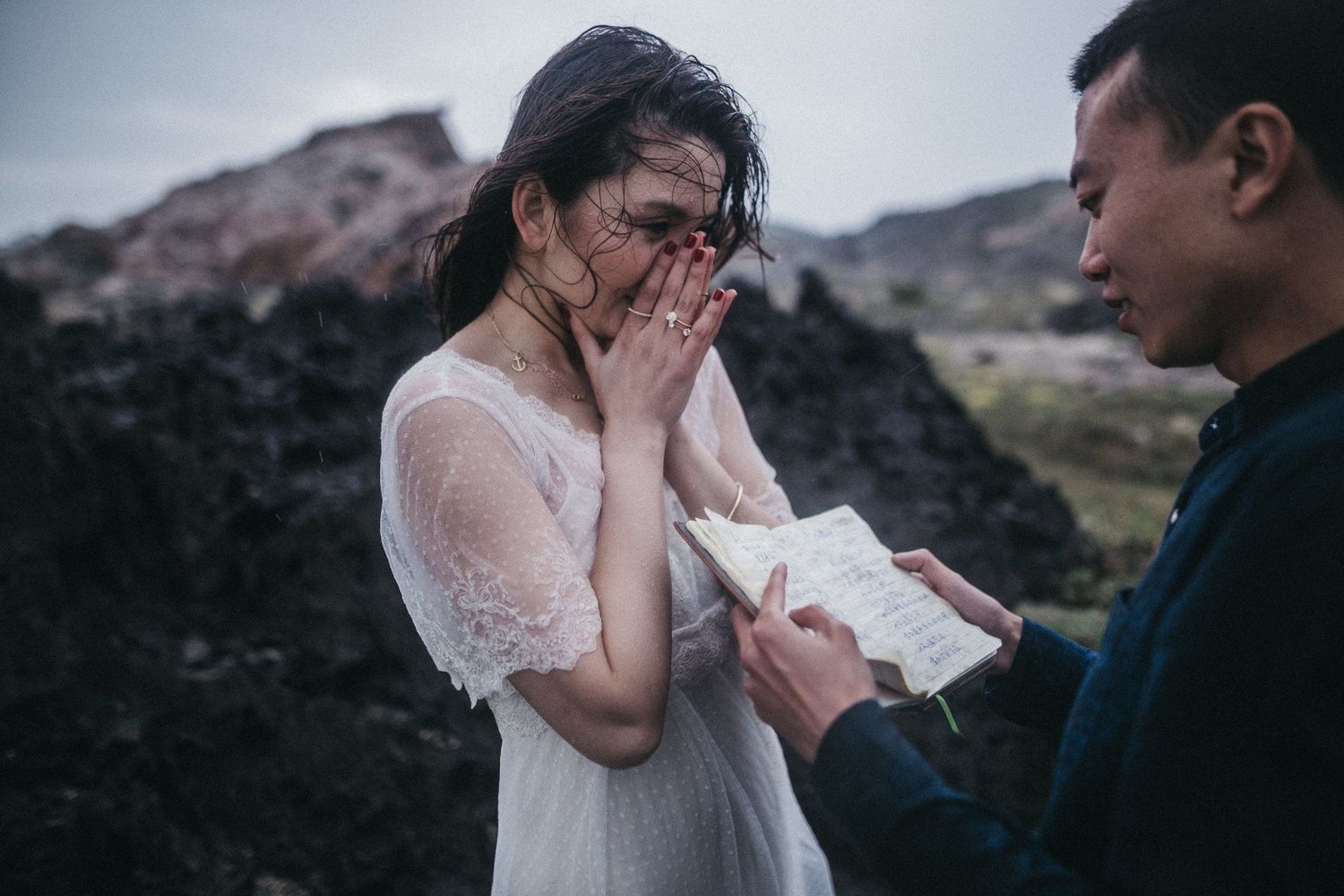 A couple shares an emotional moment during a proposal against a rocky mountain backdrop.