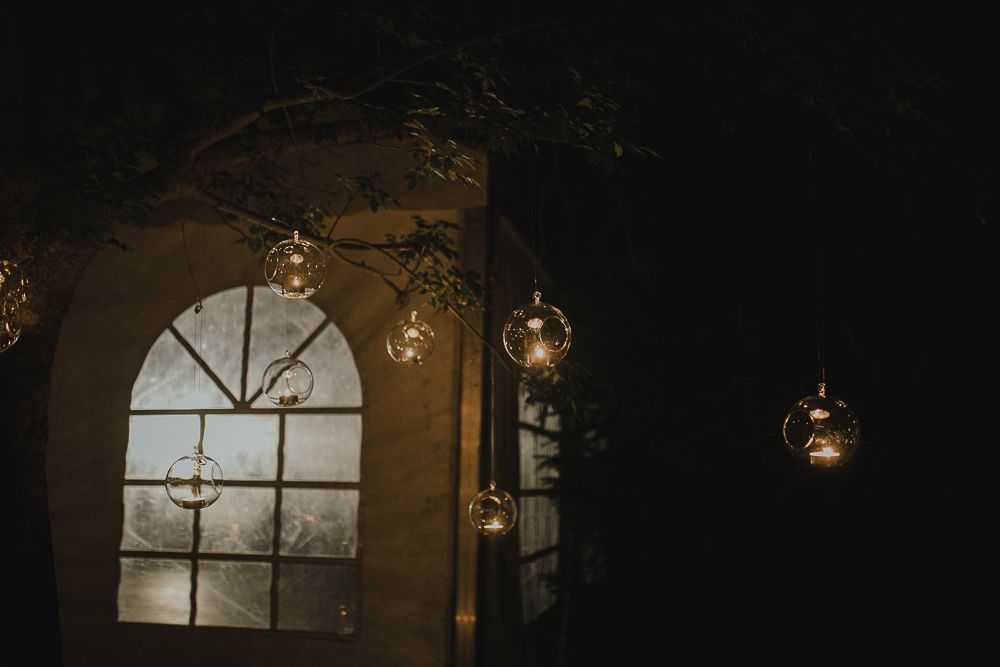 An arched window with hanging glass lanterns creates a romantic evening ambiance.