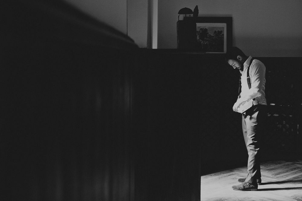 Dramatic black and white photograph of person standing in dark room.