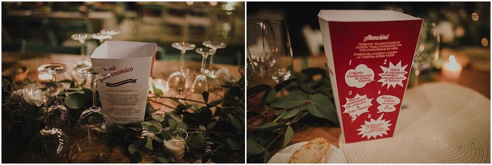 Wedding reception table settings with paper cups and decorative floral displays in dim lighting.