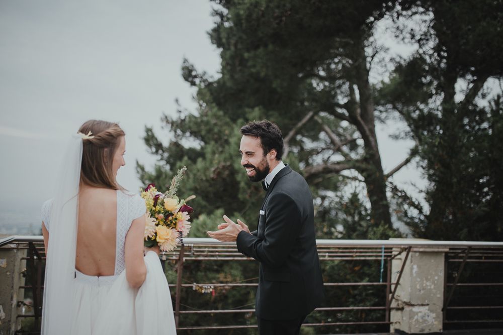 Wedding couple sharing intimate moment in elegant attire against backdrop of trees.