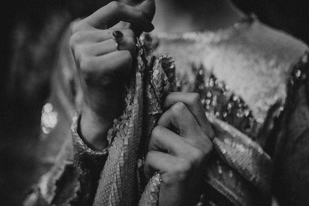Close-up black and white photograph showing hands knitting or crocheting with wool yarn.