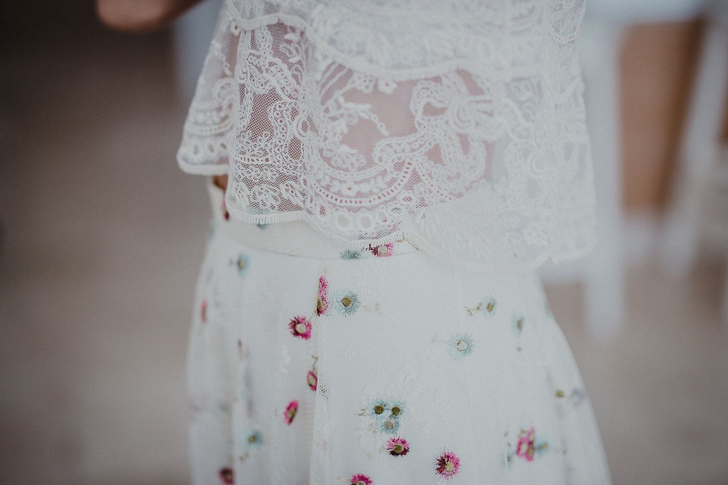 Close-up detail of delicate white lace and floral pattern on a wedding dress.