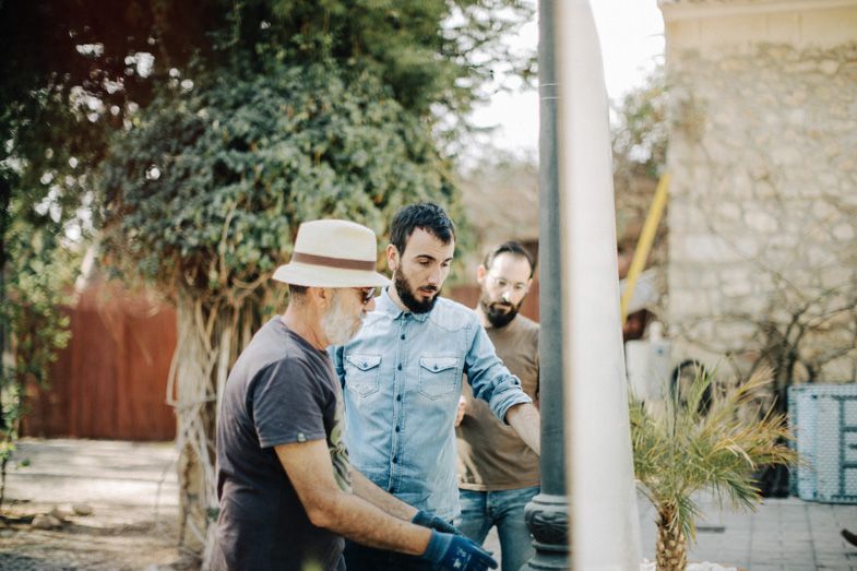 Group discussing project details in sunny outdoor garden setting.