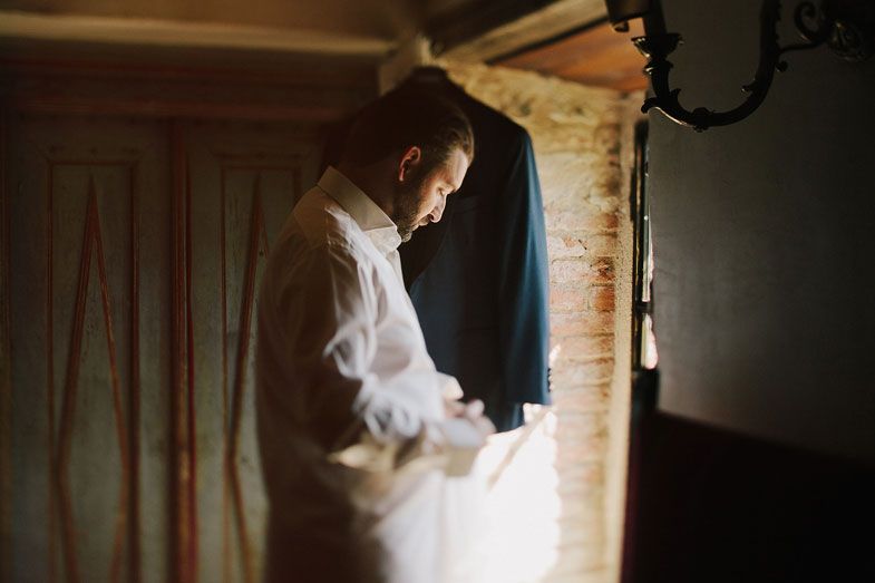 A formal suit jacket hangs in a dimly lit rustic room.