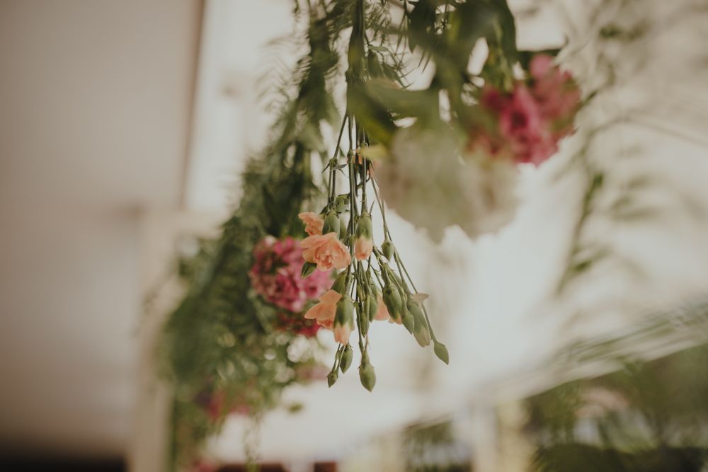 Delicate pink floral arrangements hanging from above with soft bokeh lighting effects.