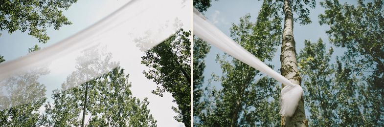 White fabric canopy installation among tall trees for an outdoor celebration.