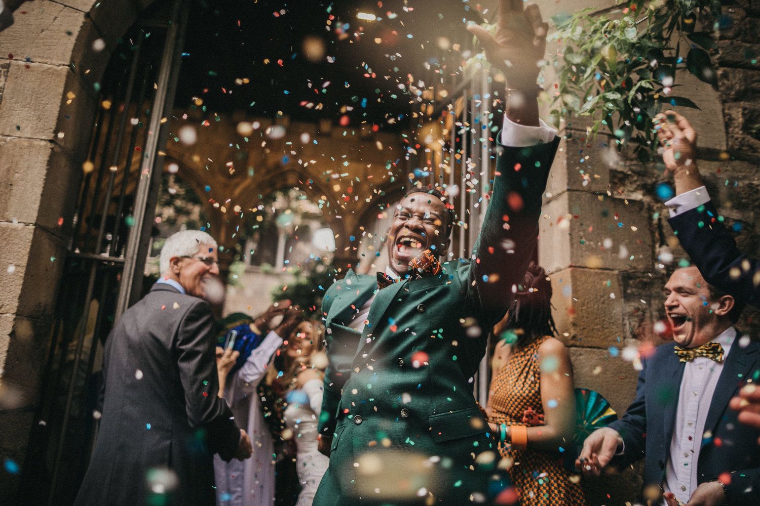 Celebratory scene with champagne spray and confetti at outdoor wedding reception.