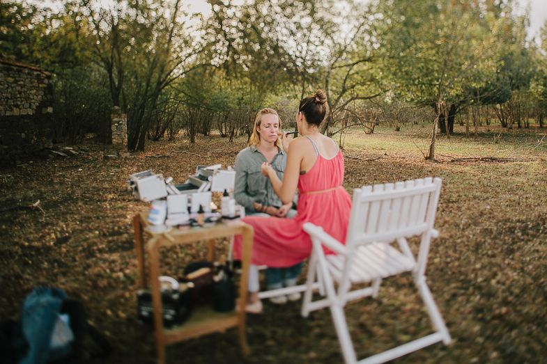 Friends enjoying an outdoor picnic with white folding chairs near a stone building.