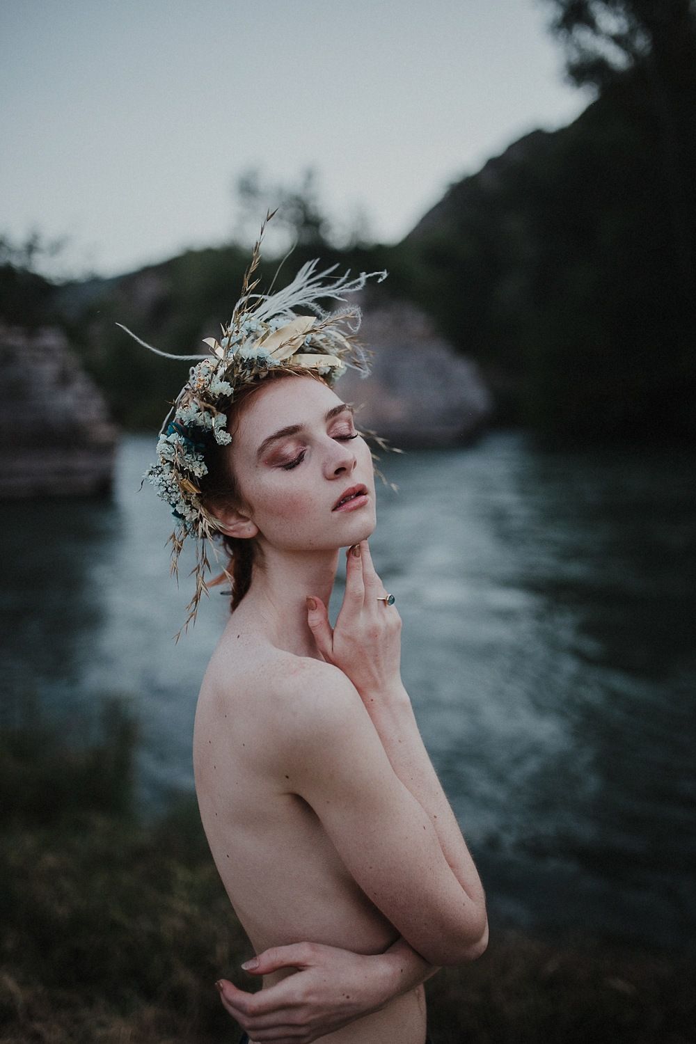 Artistic portrait with floral crown beside a misty mountain lake.