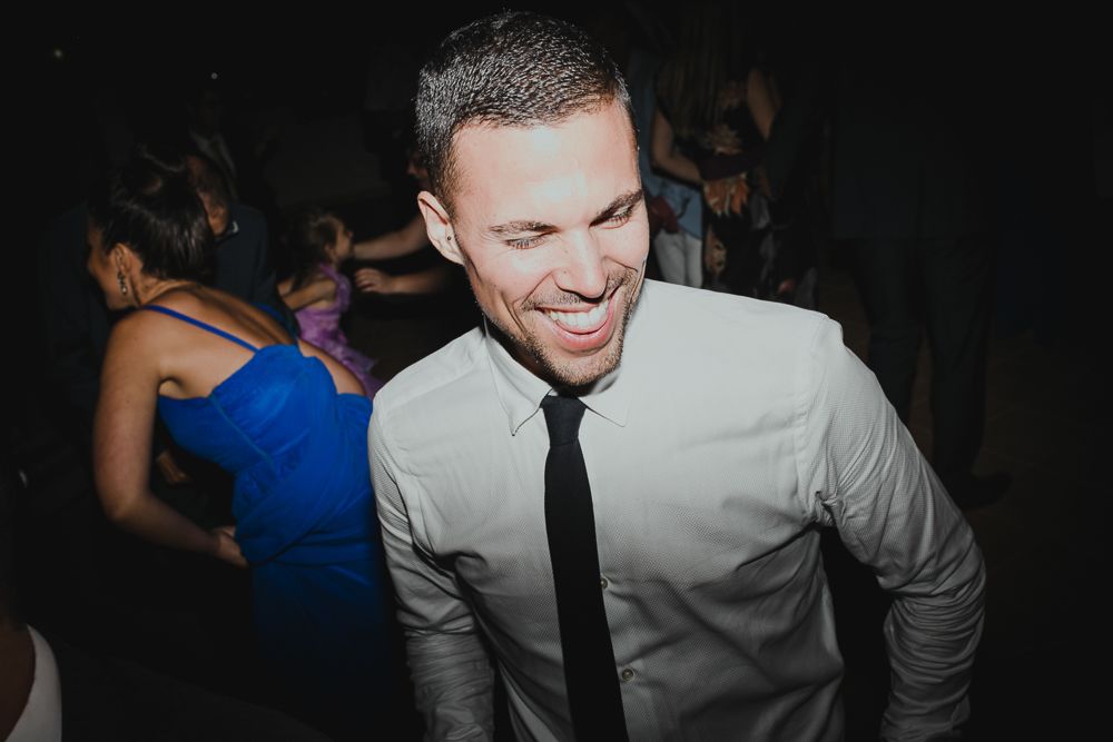 Guest in white shirt and black tie smiling during celebration event at a party.