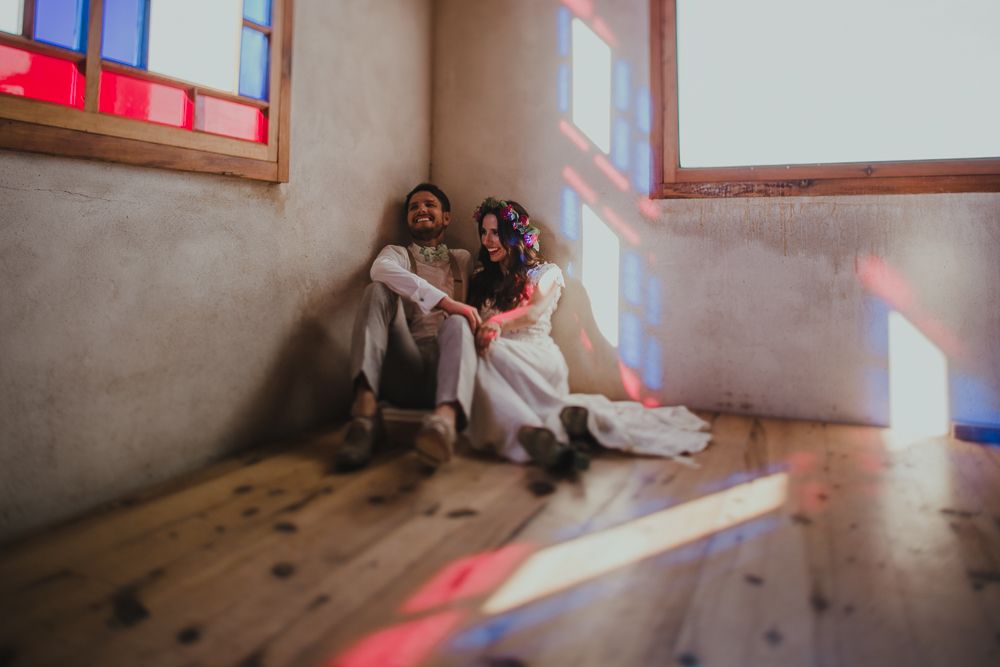 Sunlight streams through red-trimmed windows creating colorful shadows in wedding venue.