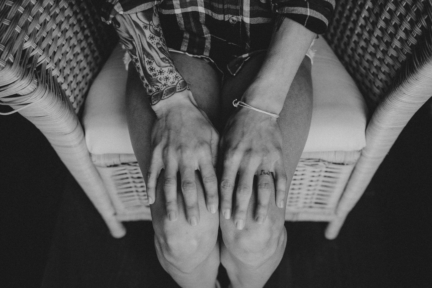 Black and white overhead view of hands resting on knees in casual attire.