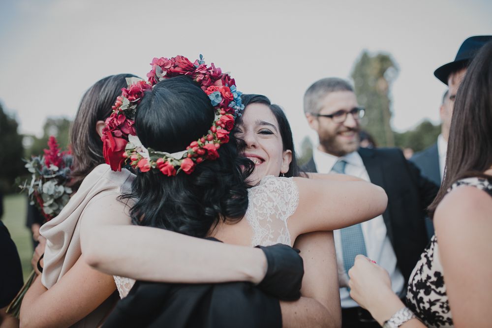 Wedding guests sharing embraces during an outdoor reception celebration.