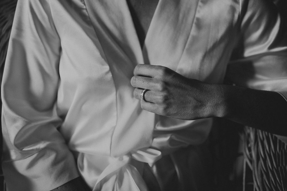 Close-up shot of hands adjusting a white formal shirt in black and white.