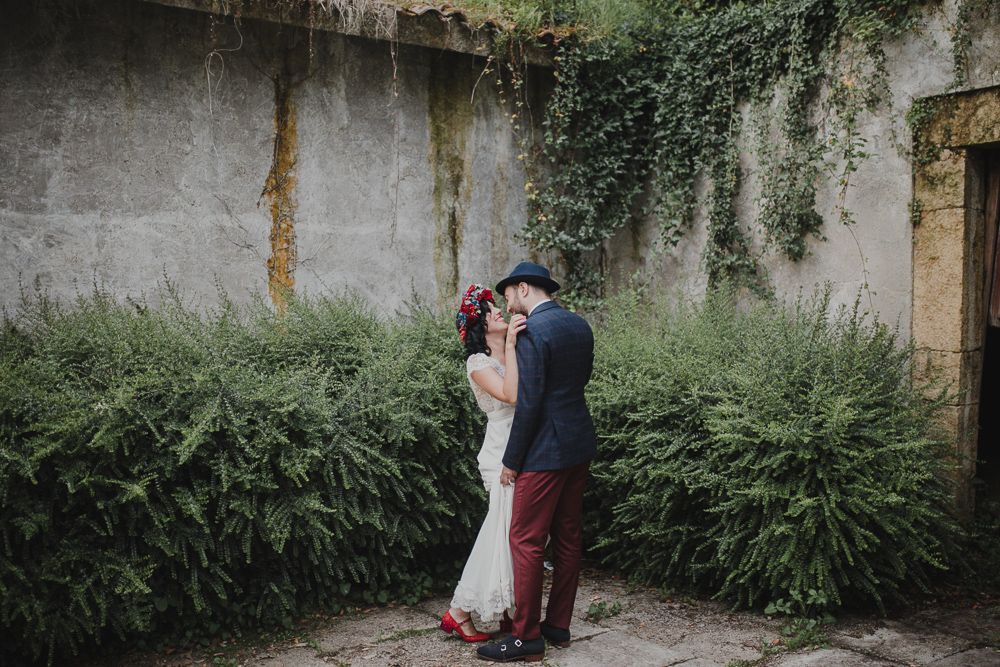 A romantic wedding moment captured against a vine-covered wall with ferns.