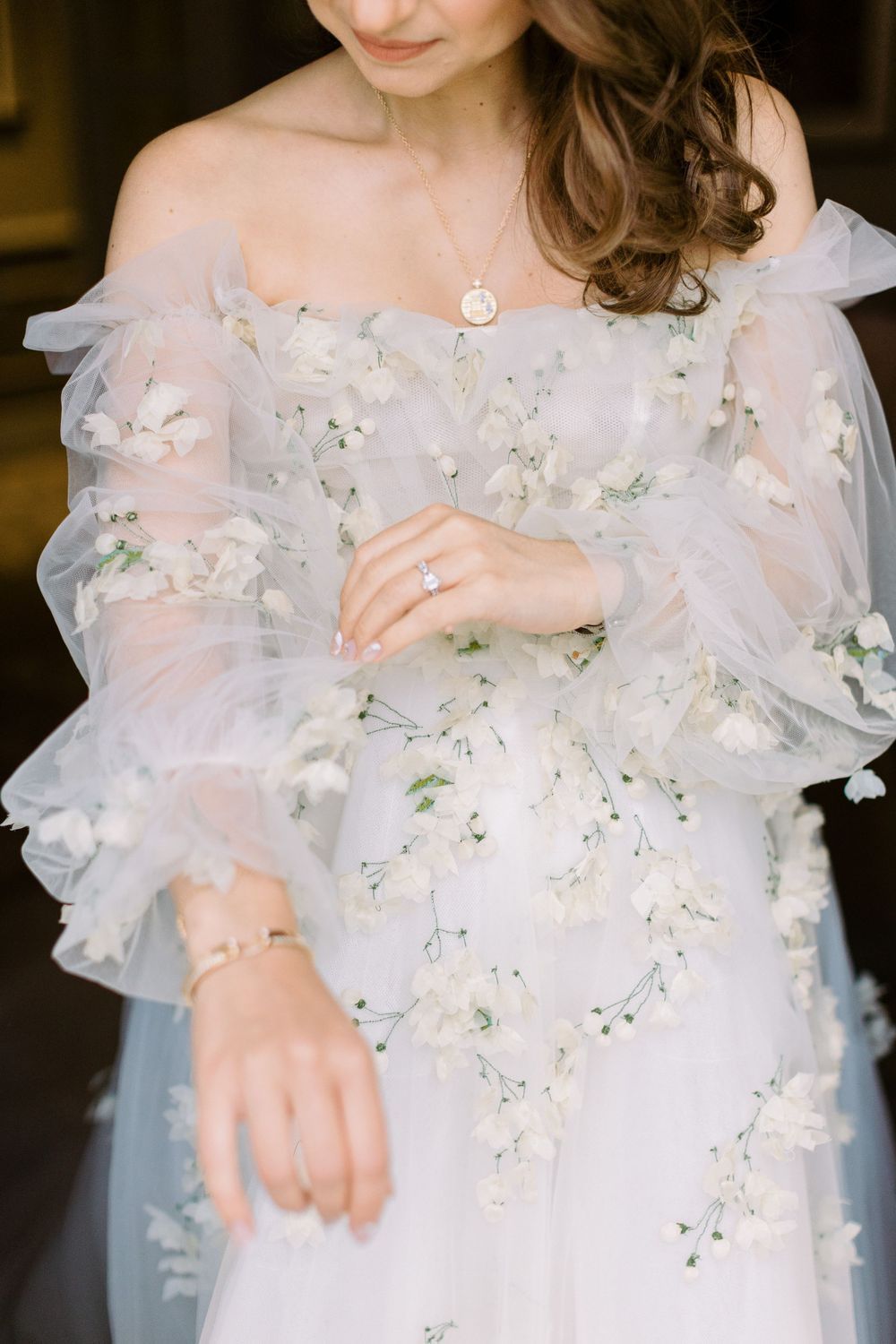 Delicate floral embellishments on ethereal white wedding gown with sheer sleeves.
