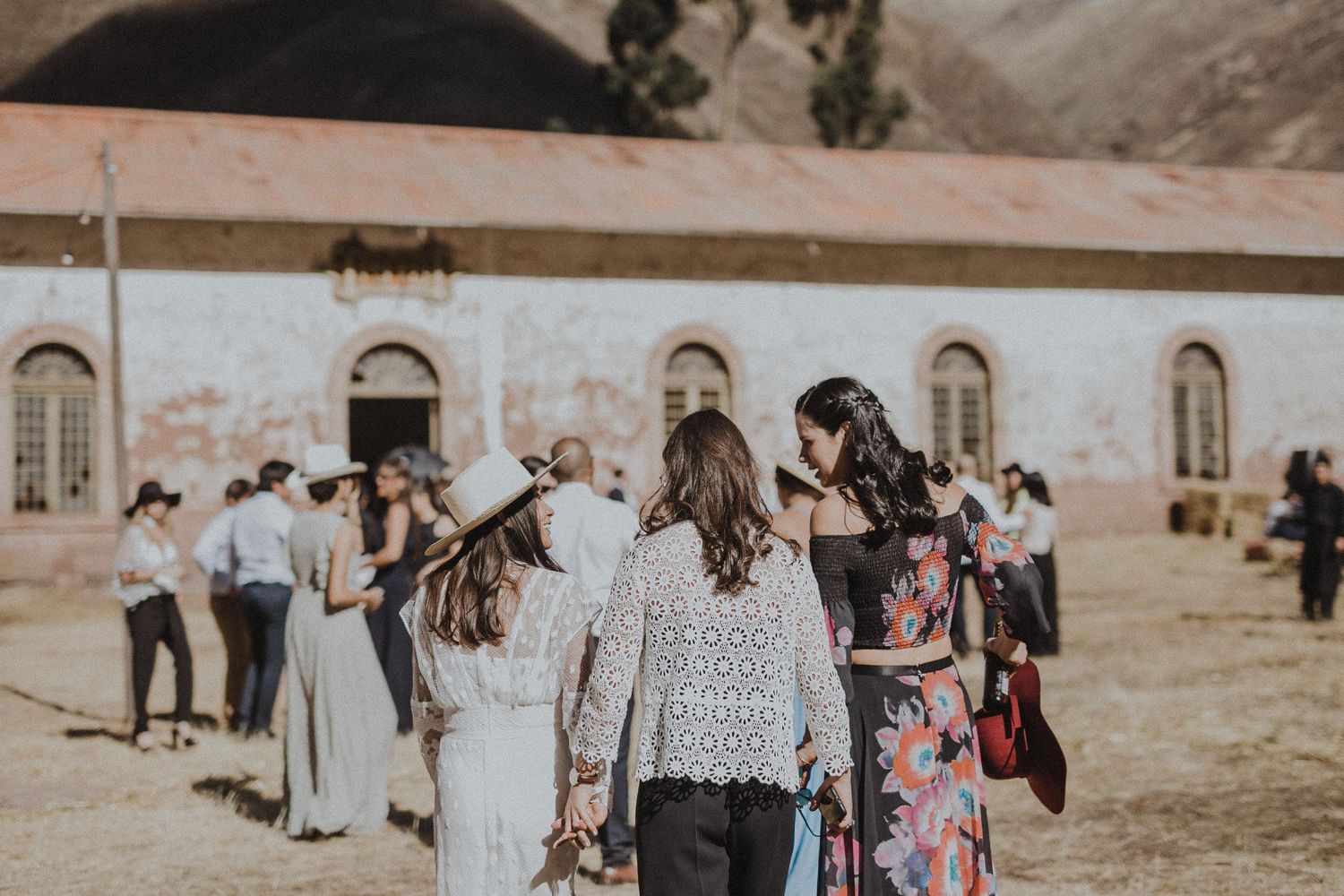 Wedding guests gathering outside a historic building during a sunny afternoon.