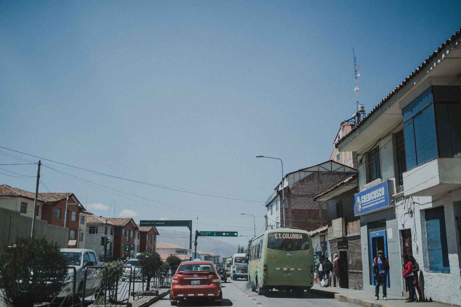 Street view of small town with cars, buildings and blue sky.