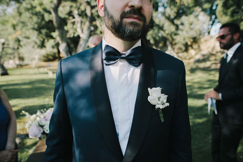 Close-up of groom in classic black tuxedo with white boutonniere.