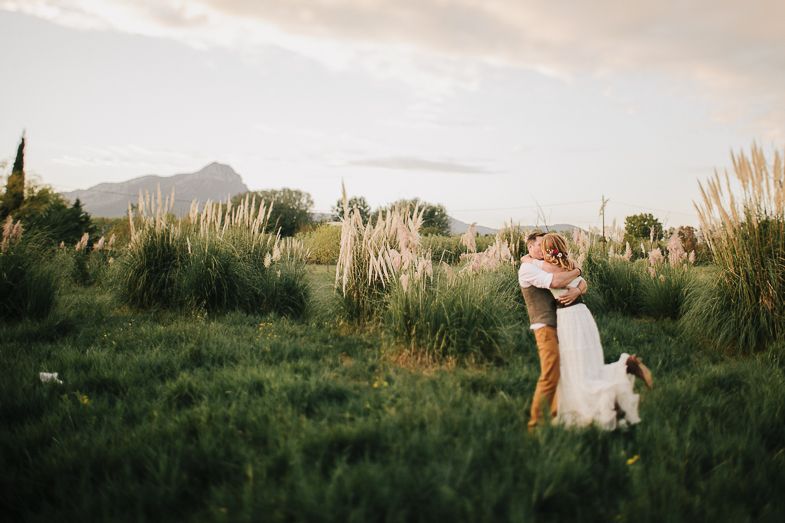 A romantic moment captured in a field with mountains and pampas grass in the background.