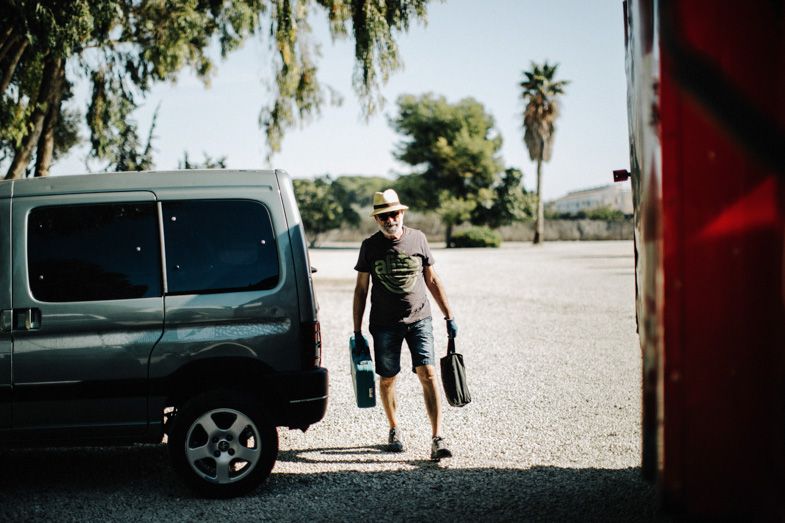 Person loading flowers into a van on a sunny day.