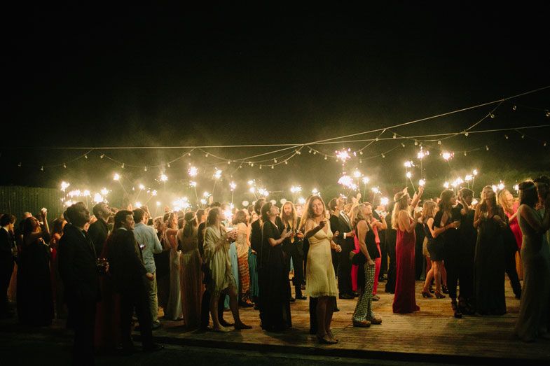 Large crowd of wedding guests gathered under string lights at an outdoor nighttime celebration.