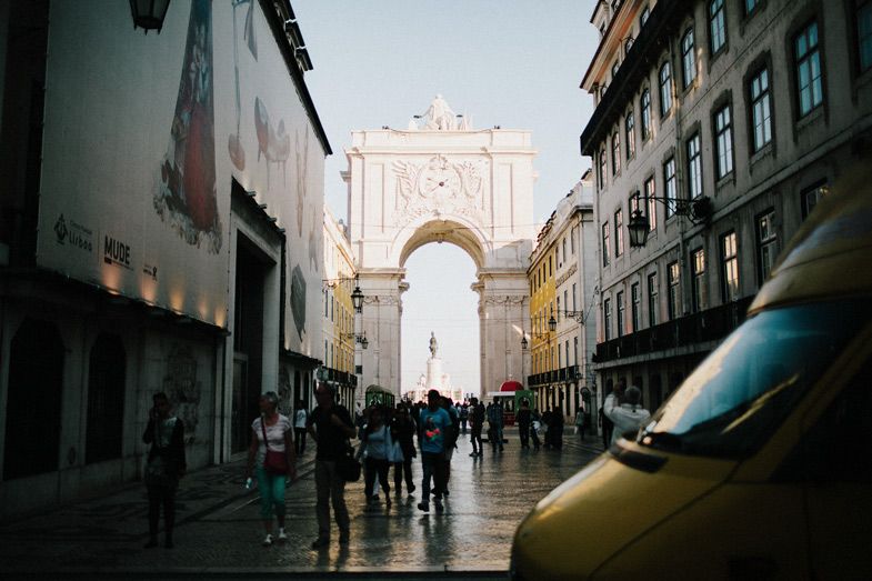 Wet cobblestone street leading to Rua Augusta Arch in Lisbon.