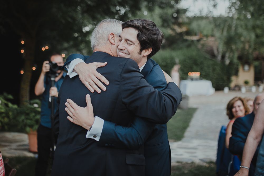 An emotional embrace between wedding guests during an outdoor celebration.