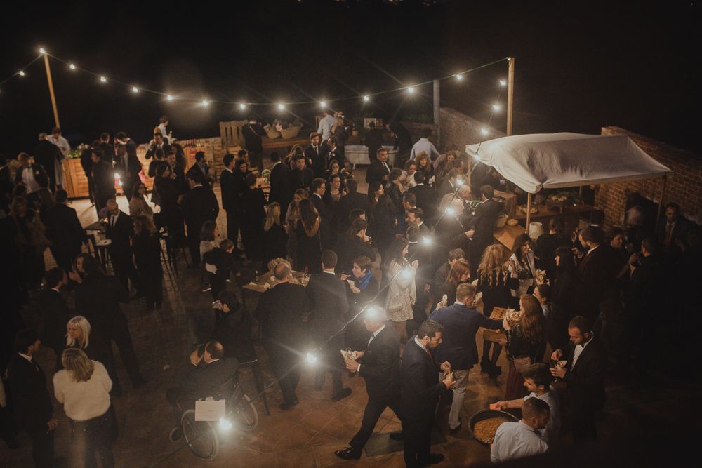 Crowded outdoor night event with string lights and dancing silhouettes.