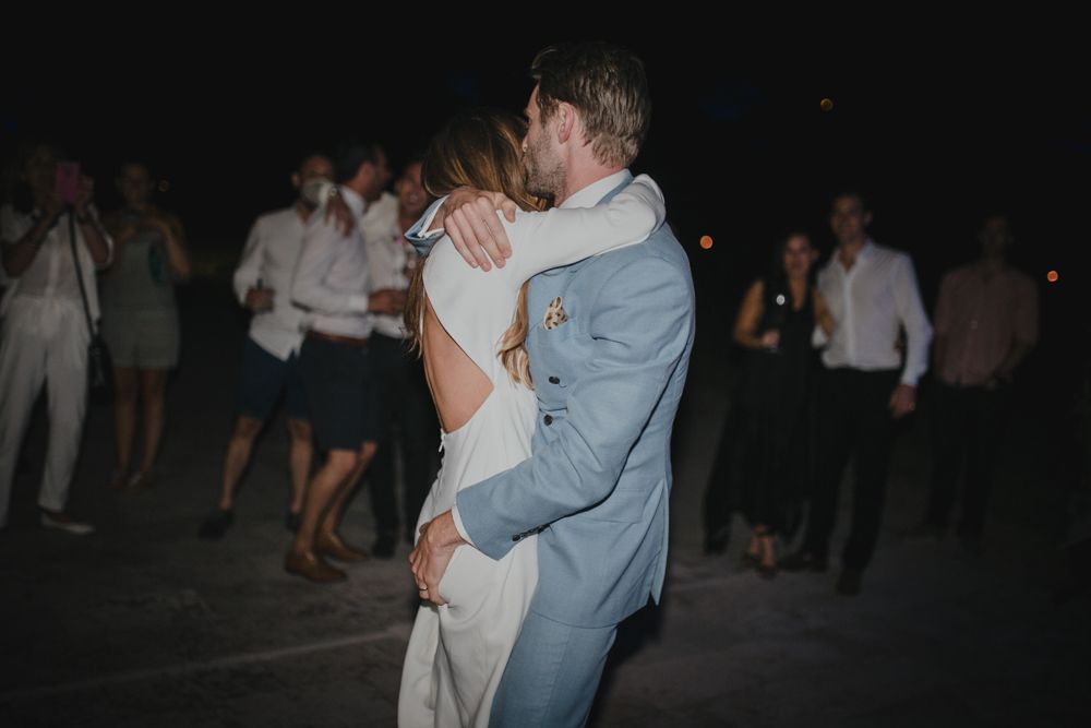 A couple embraces while dancing at an outdoor evening celebration.