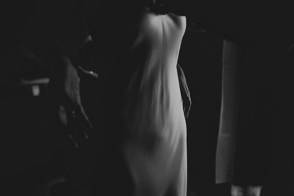 Artistic black and white photograph of a wedding dress in dramatic lighting.