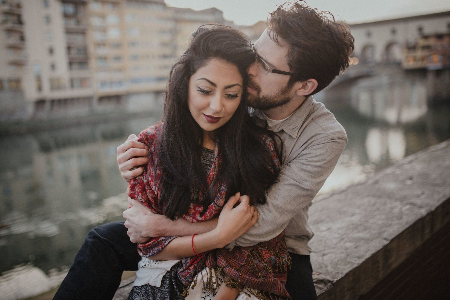 Intimate couple moment captured along riverside in Florence, Italy.